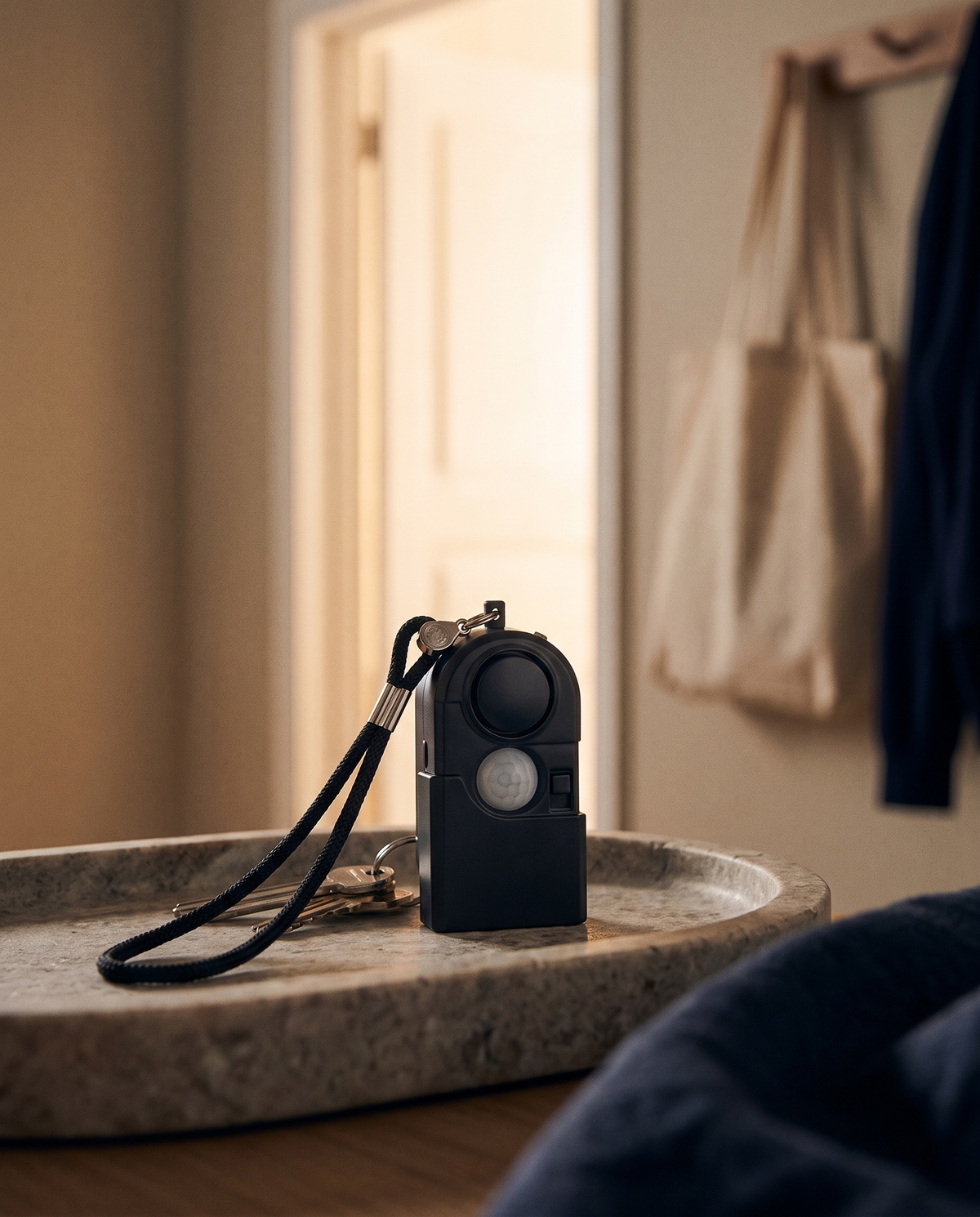 Mini alarme personnelle SOS noire TravelShield accrochée à des clés sur un vide-poche